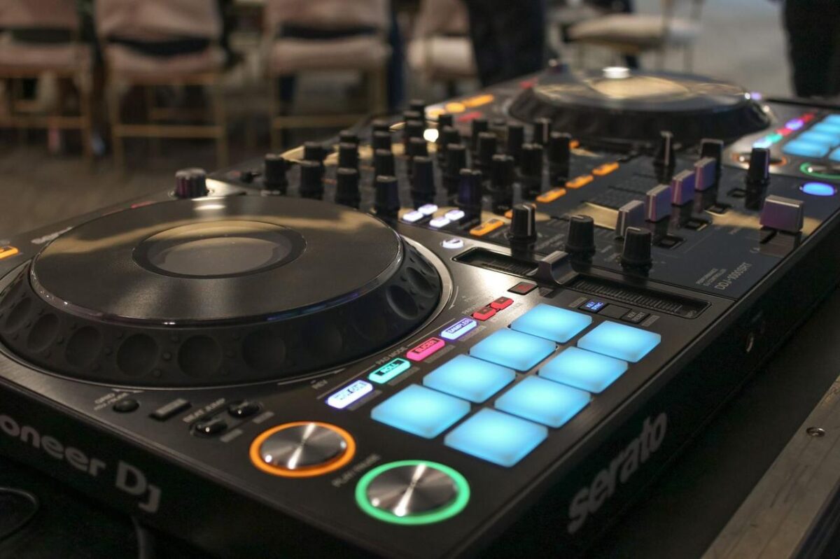 Primer plano de una consola de mezclador DJ Pioneer con botones y diales iluminados en un entorno de estudio (imagen de referencia)