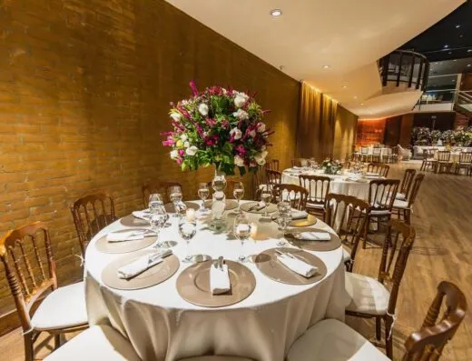 Interior de restaurante de lujo con configuración de mesa elegante y centro de mesa floral. Ambiente perfecto para recepciones y eventos.