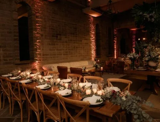 Salón de eventos rústico con mesas elegantemente decoradas para una reunión sofisticada.