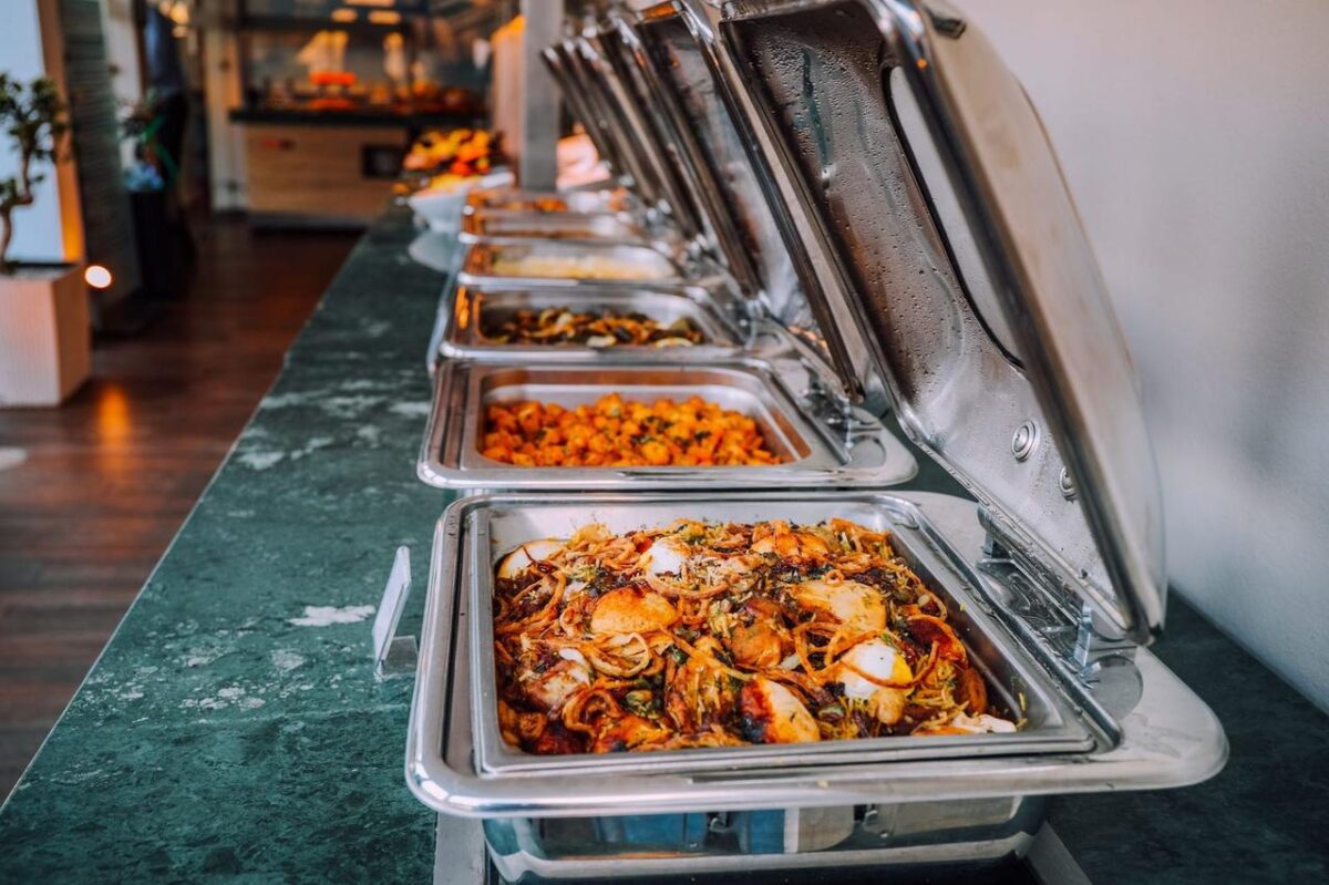 Una elegante disposición de buffet con varios platos deliciosos en bandejas de acero inoxidable, perfecto para eventos (imagen de referencia)