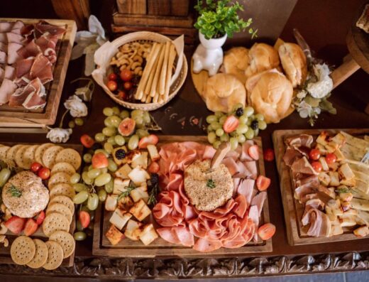 Una tabla de charcutería bellamente dispuesta con carnes, quesos, frutas y pan para eventos de catering.