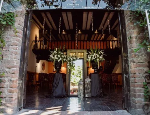 Una entrada elegante a un lugar de boda adornada con arreglos florales y decoración con estilo.