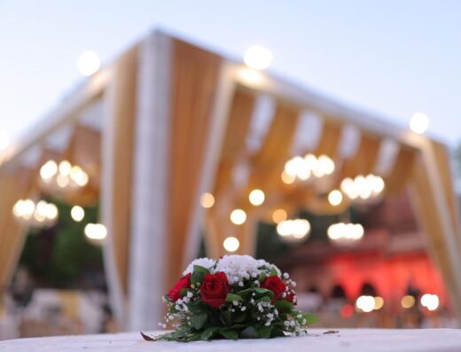 Hermoso lugar de boda al aire libre con centro de mesa de rosas rojas y candelabros.