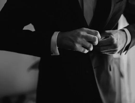 Un primer plano en monocromo de un hombre ajustando su chaqueta de traje formal, irradiando estilo y clase.