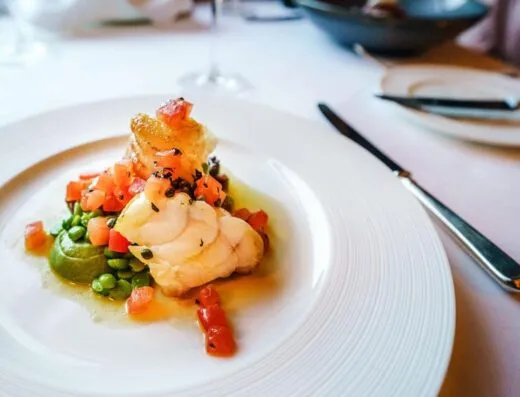 Elegante plato gourmet de pescado con guisantes y tomates, presentado de manera artística. Perfecto para entusiastas de la cocina.