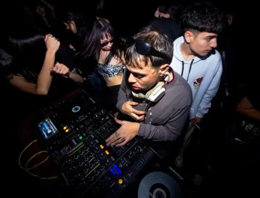 Un dinámico set de DJ con un público animado disfrutando de la música electrónica en una discoteca argentina.