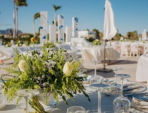 Sofisticada escena de boda al aire libre con arreglos florales y elegante montaje de mesas.