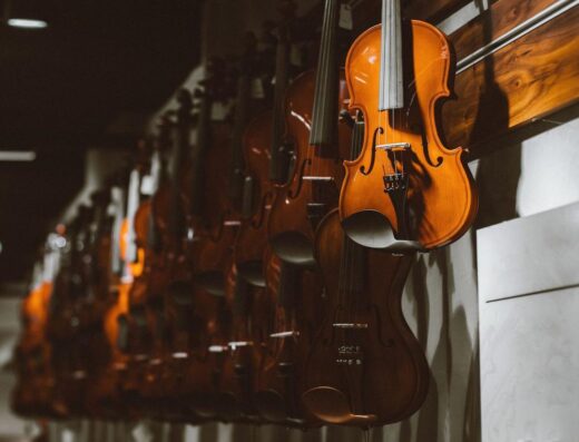 Fila de violines colgados en una pared en una tienda de música, mostrando instrumentos de cuerda.