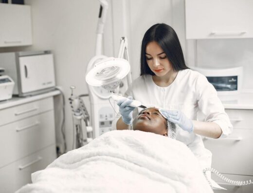 Esteticista proporcionando un tratamiento facial rejuvenecedor a una clienta en un moderno entorno de clínica de spa.