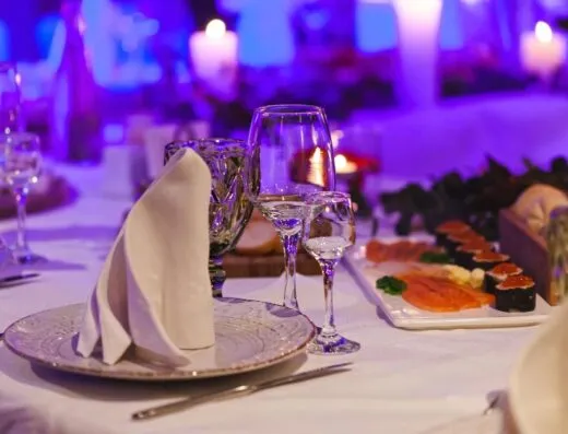 Arreglo de mesa sofisticado con plato de sushi, velas y elegantes cristalerías, perfecto para un ambiente de cena elegante.