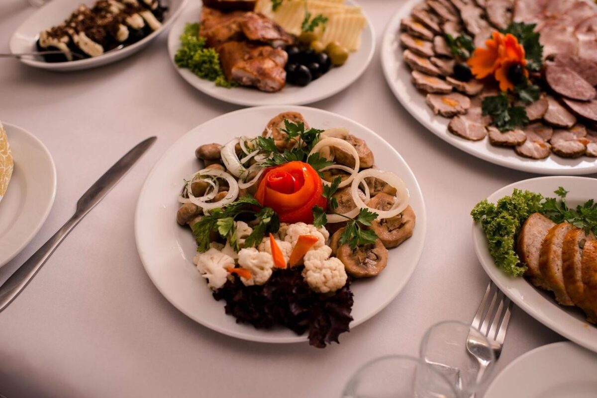 Platos gourmet bellamente dispuestos con carnes, quesos y guarniciones en una mesa blanca (imagen de referencia)