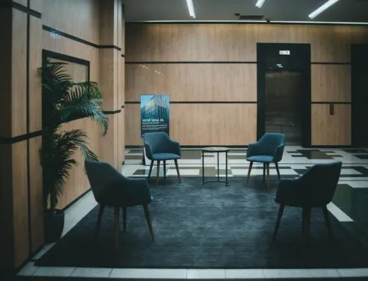 Un vestíbulo de oficina elegante con sillas modernas y un diseño minimalista en un tono neutro.