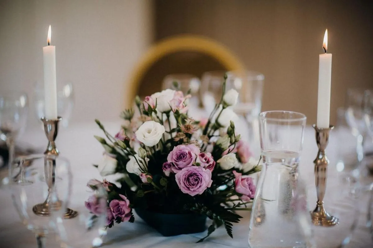 Hermoso centro de mesa floral con velas en una mesa de boda (imagen de referencia)