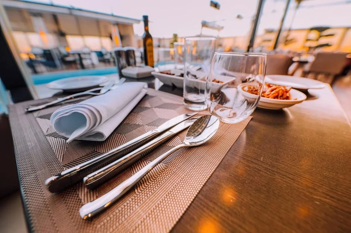 Primer plano de una elegante mesa puesta en un elegante restaurante al aire libre con iluminación ambiental (imagen de referencia)