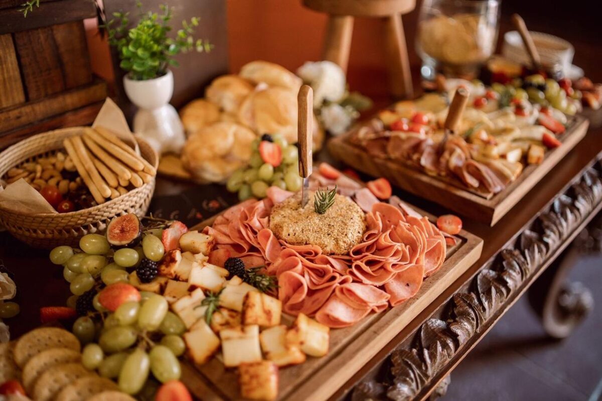 Deliciosa tabla de charcutería con carnes, quesos y frutas frescas en un montaje de evento (imagen de referencia)