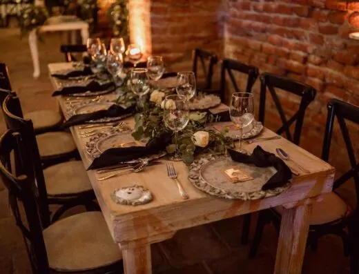 Una mesa de boda rústica bellamente decorada con vajilla elegante y decoración floral.