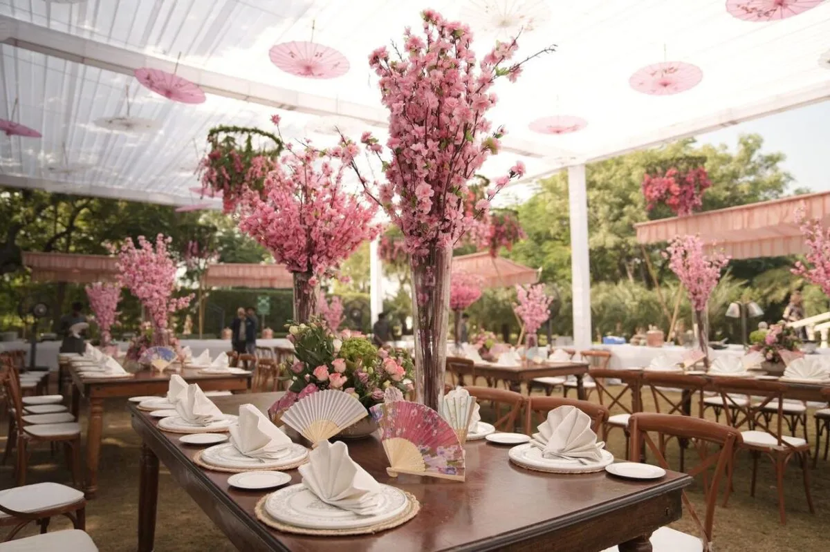 Impresionante configuración de boda india al aire libre con decoración floral rosa y abanicos tradicionales (imagen de referencia)