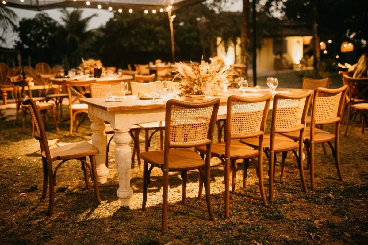 Mesas de recepción de boda al aire libre, bellamente arregladas bajo cálidas luces nocturnas (imagen de referencia)