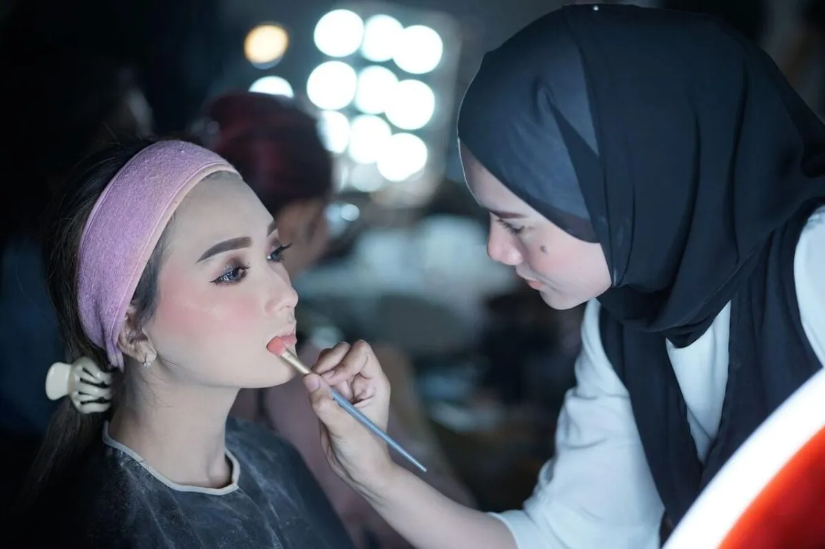 Una maquilladora aplicando lápiz labial a un modelo en un estudio de belleza (imagen de referencia)