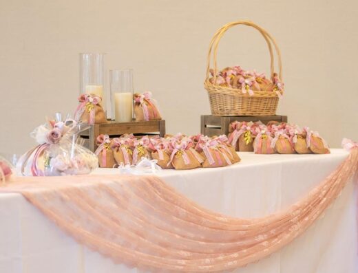 Una mesa bellamente decorada con bolsas de regalo, velas y tela rosa drapeada para una ocasión especial.