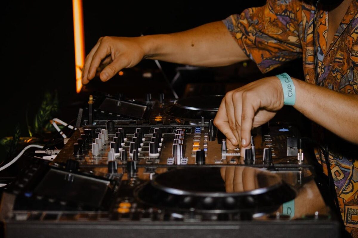 Primer plano de las manos del DJ mezclando música en un evento vibrante en un club nocturno (imagen de referencia)