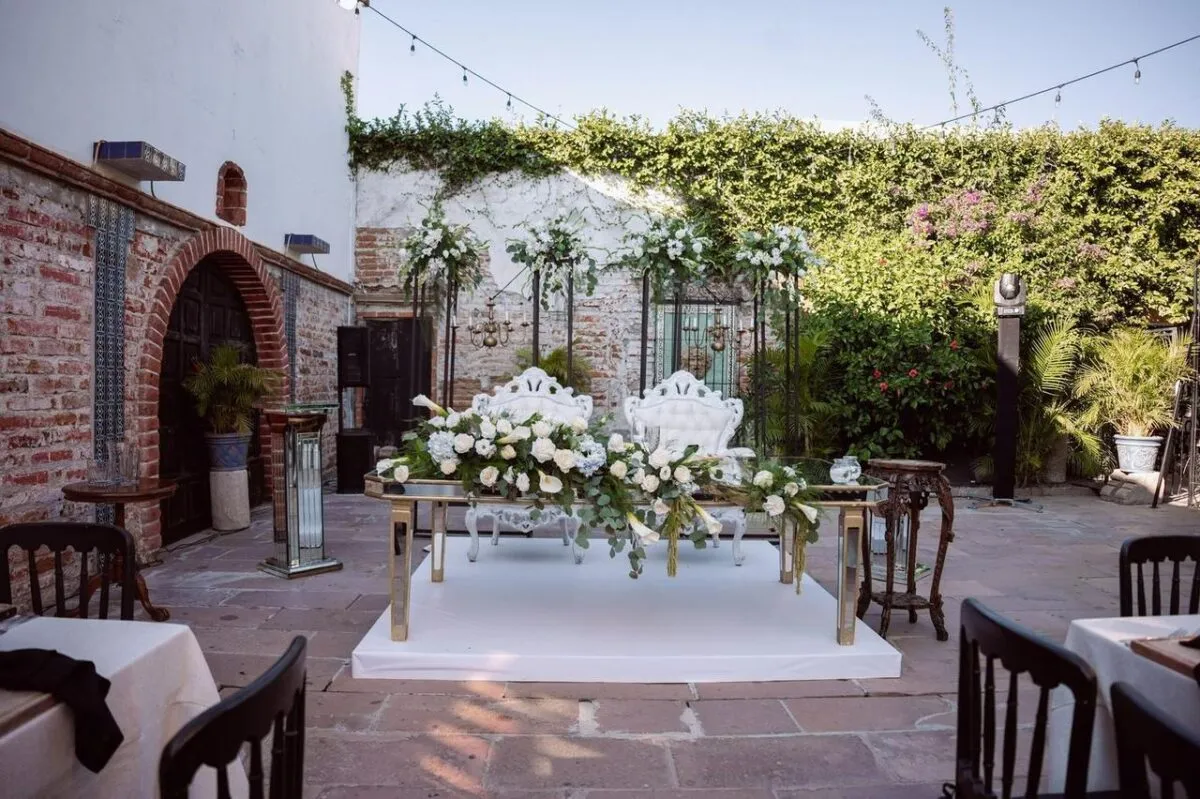 Hermosa organización de boda con elegantes arreglos florales y asientos en un patio al aire libre (imagen de referencia)