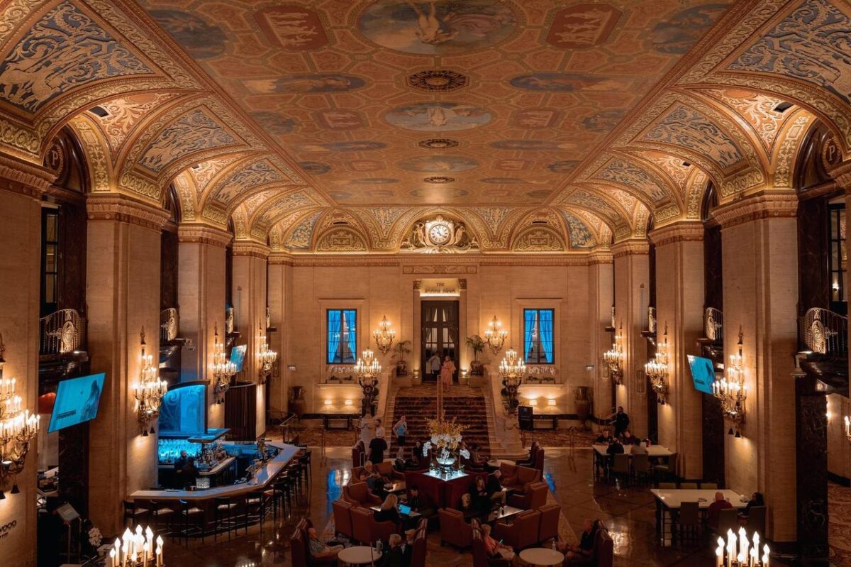 Lobby de hotel lujoso con techo ornamentado y elegantes candelabros (imagen de referencia)