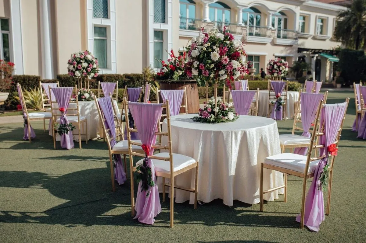Hermosa área de recepción de boda al aire libre con arreglos florales y sillas de lavanda (imagen de referencia)