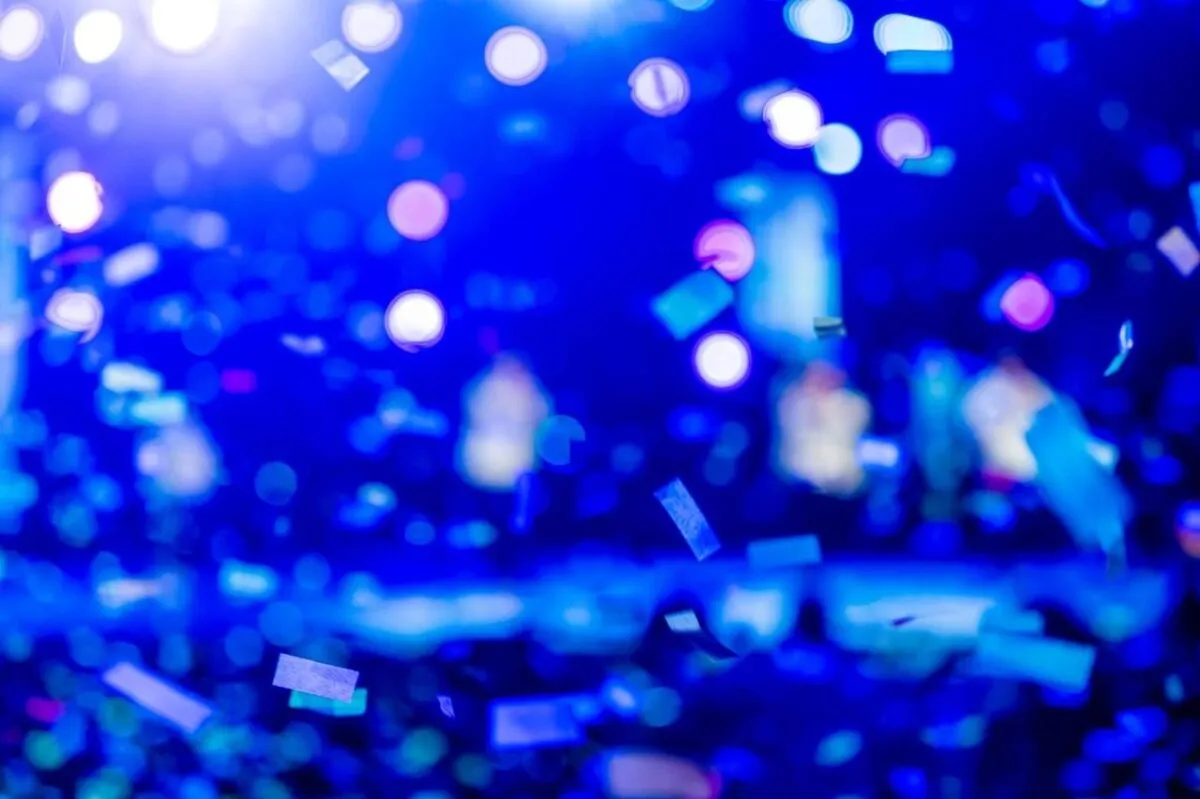 Una toma dinámica de confeti de colores y luces bokeh azules, que captura una atmósfera festiva (imagen de referencia)