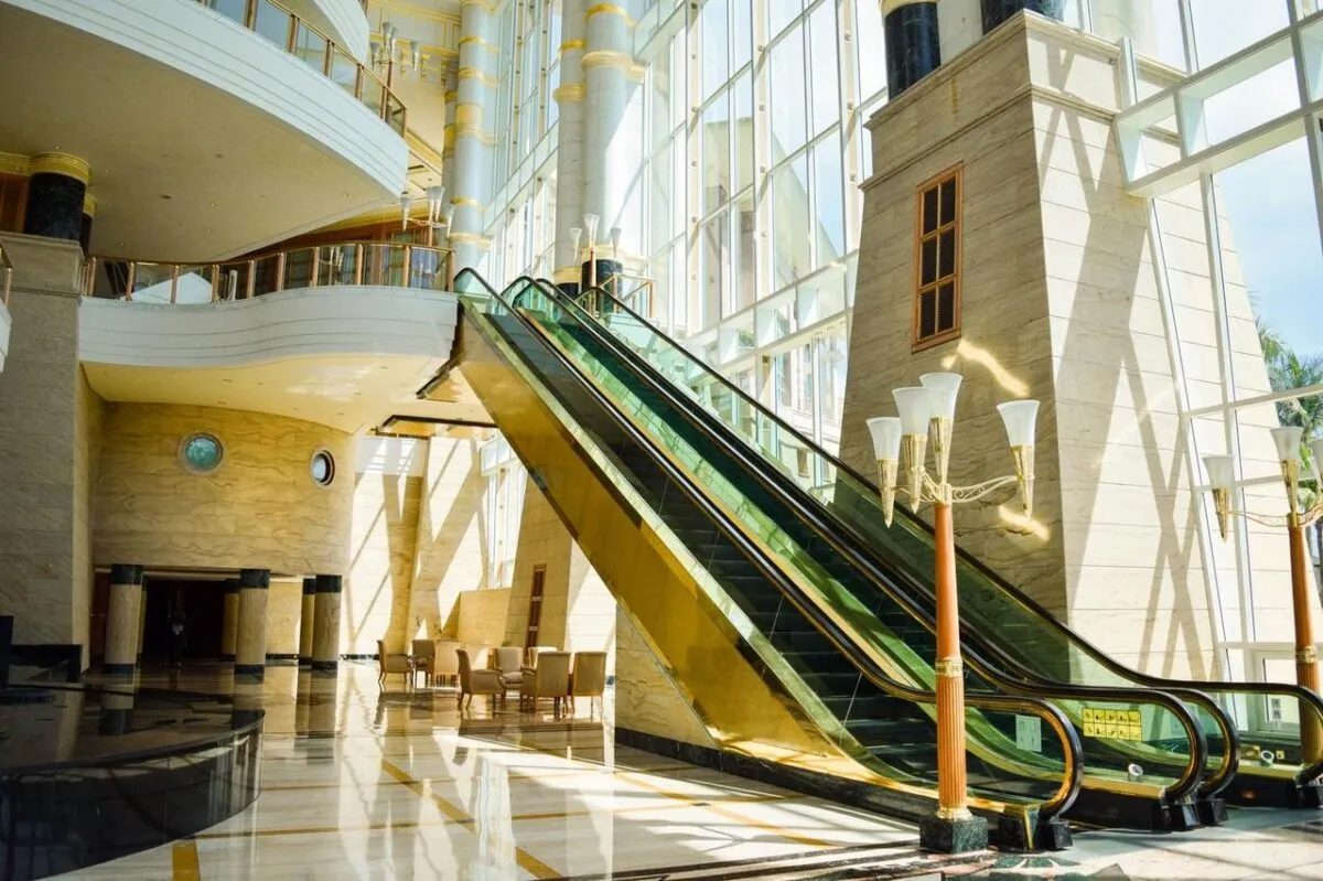 Una escalera mecánica de vidrio moderna en un espacioso atrio con luz natural brillante (imagen de referencia)
