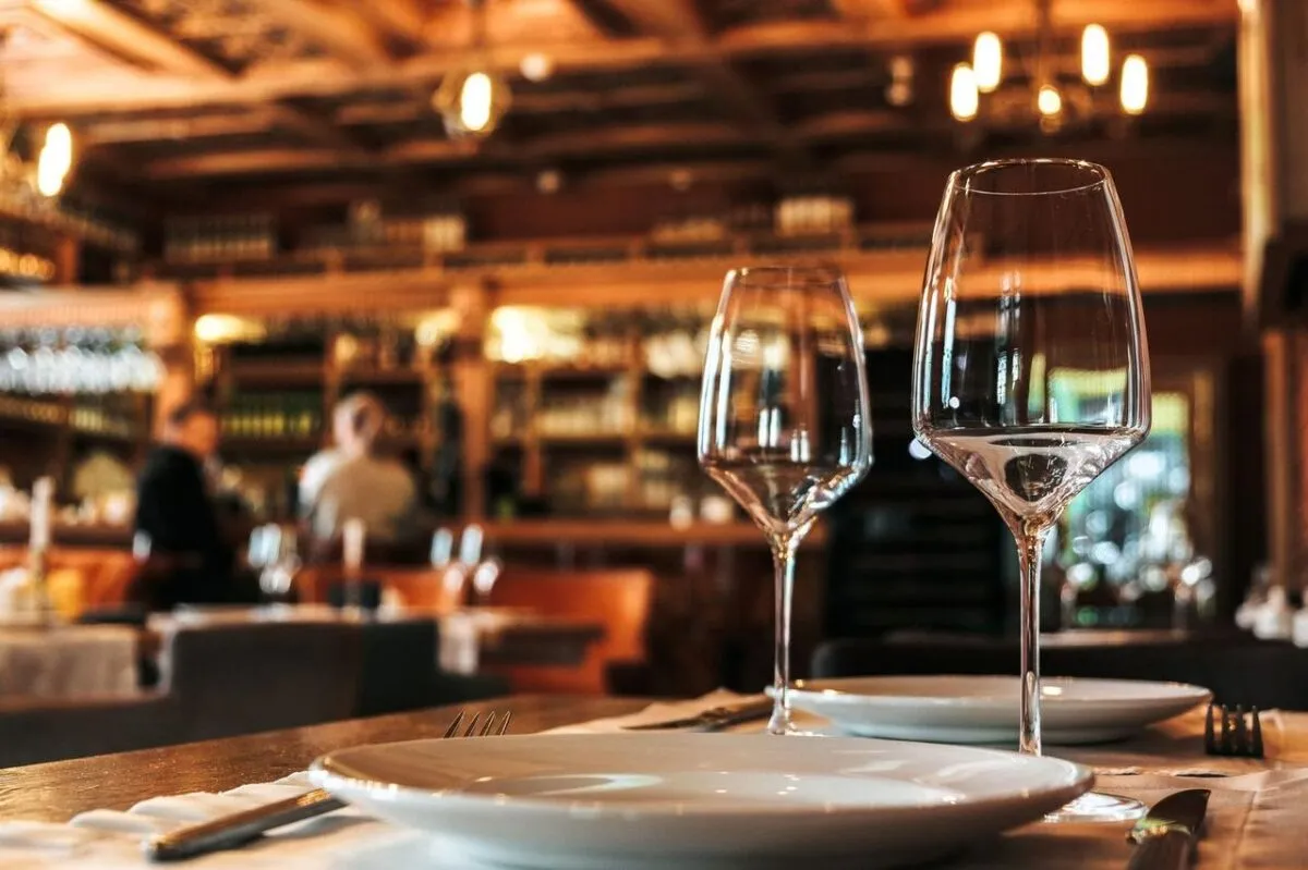 Mesa de comedor elegantemente decorada con cristalería en un ambiente acogedor y cálido de restaurante (imagen de referencia)