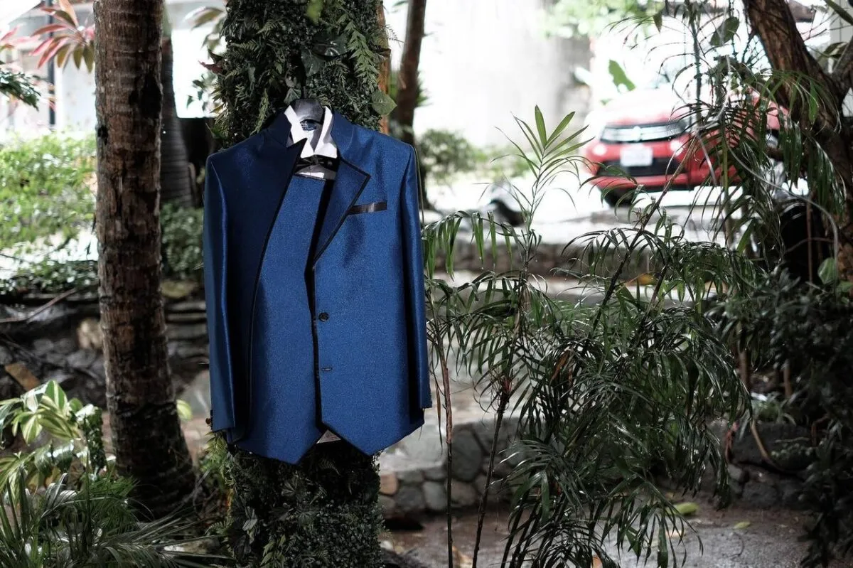 Un traje azul elegante cuelga en un árbol al aire libre, rodeado de exuberante vegetación (imagen de referencia)